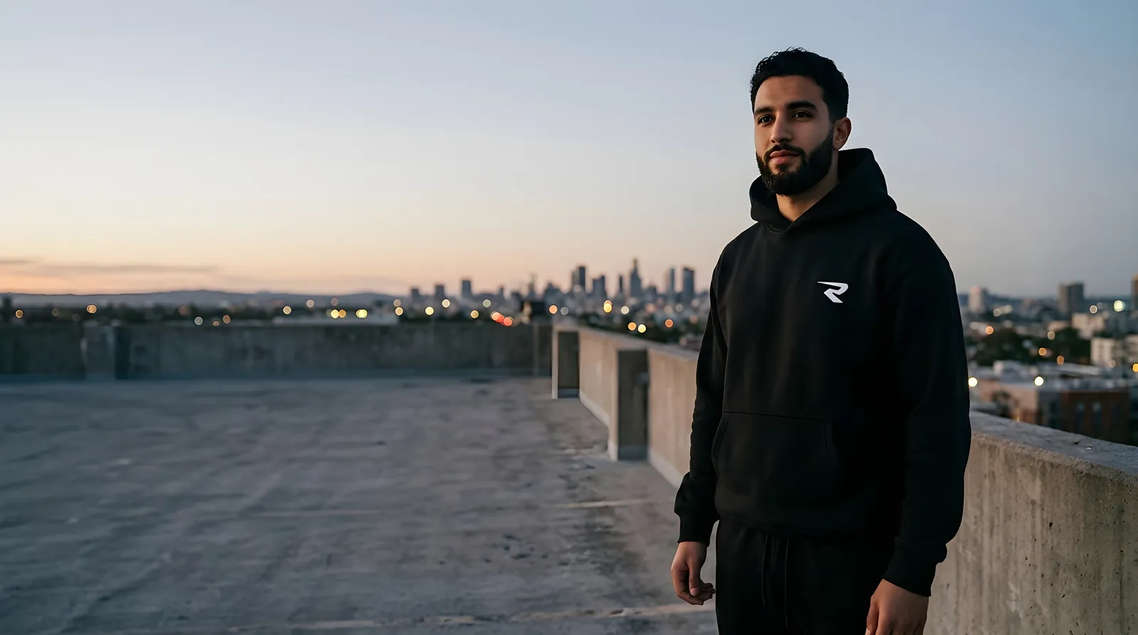 Un homme en Hoodie R-01 noir sur un toit, à la tombée du jour
